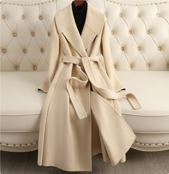 A gray wool coat with a belt, displayed on a white coat rack, with a dark collar visible.